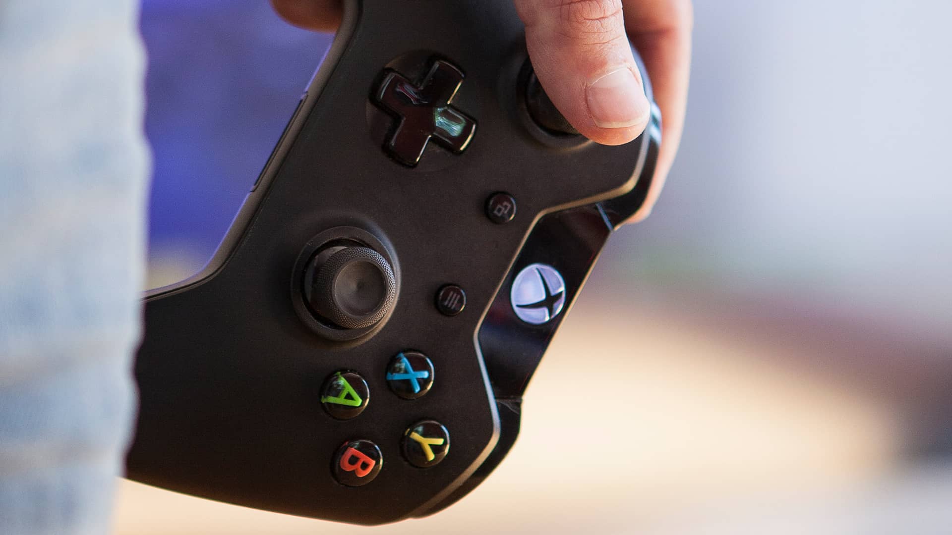 Hombre sosteniendo un mando de la consola Xbox Series X mientras decide qué juego jugar de entre los mejores que tiene esta plataforma disponibles