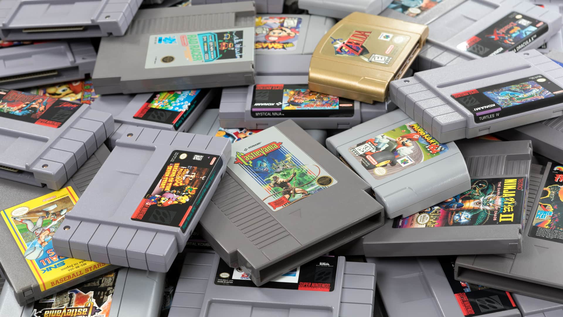 Pile of Nintendo cartridges among which the golden cartridge of The Legend of Zelda Ocarina of Time stands out, one of the best video games in history