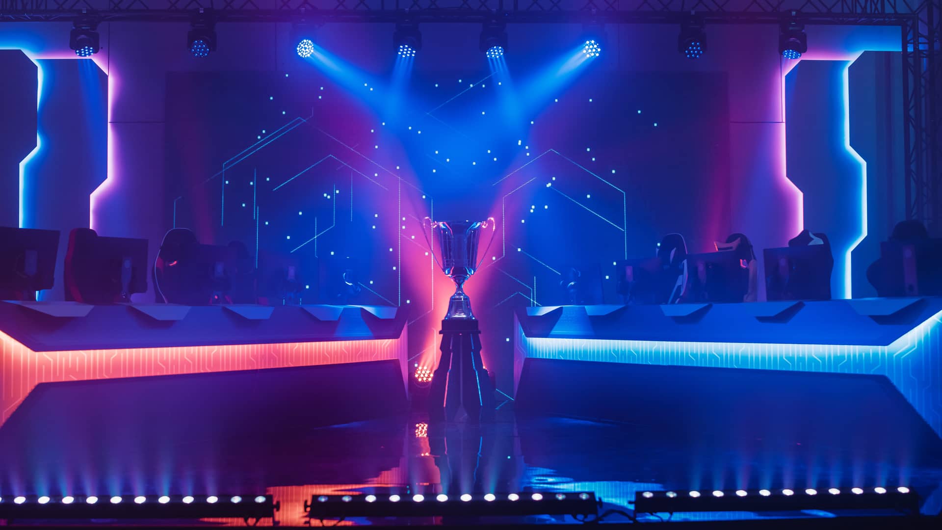Escenario de un torneo de videojuegos con una estetica futurista y luces de colores iluminando el trofeo